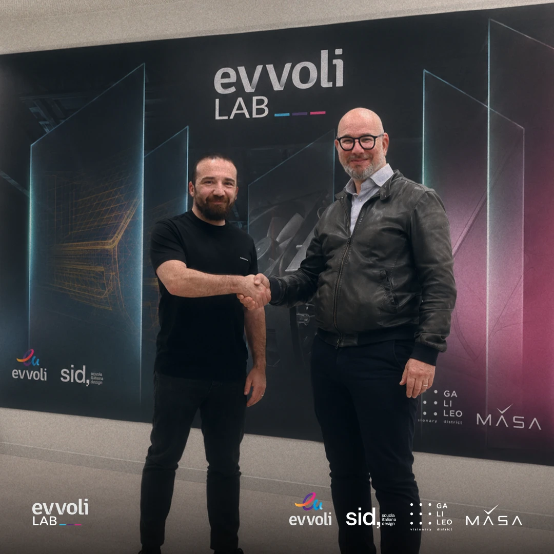 Two people shaking hands in front of the evvoliLab wall, with the evvoli, SID, Galileo Visionary District and MASA logos