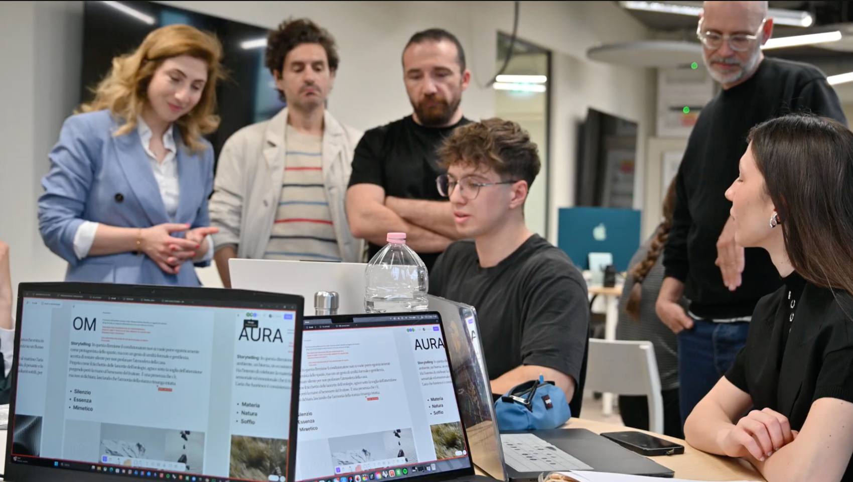 A mentor and students gathered around laptops during a co-design review session